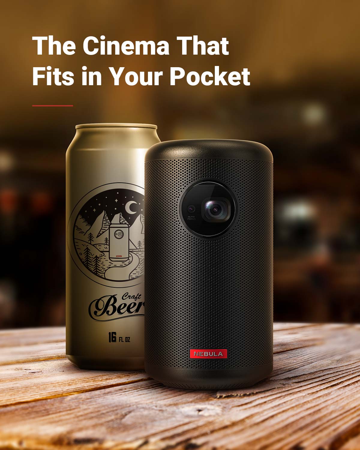 A Nebula Capsule II portable projector sits on a wooden table next to a can of beer.