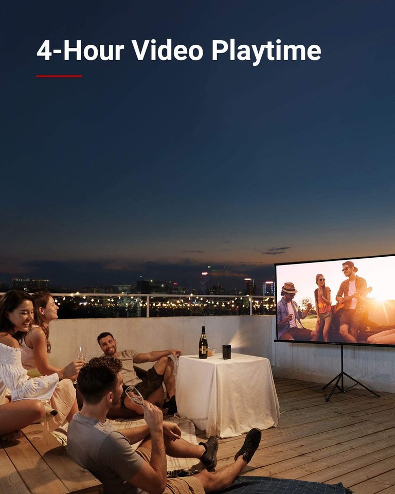 A group of friends drinks wine at night on a rooftop while using a Nebula Apollo portable projector to watch a movie.
